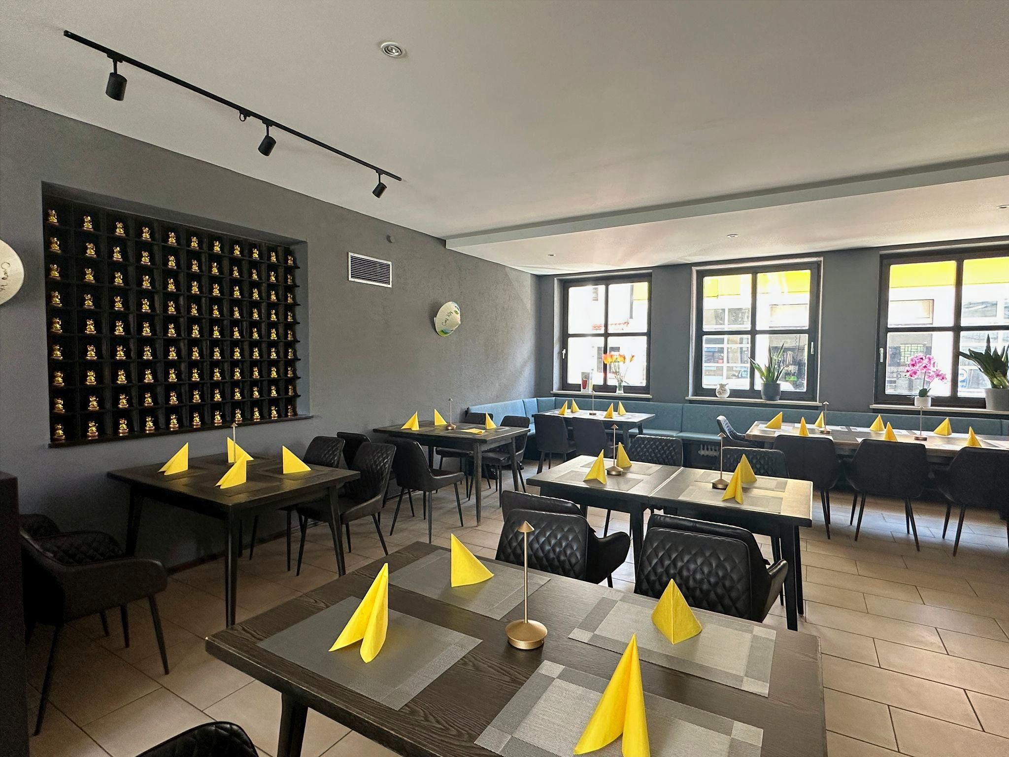 Gastraum des Bep Viet mit Wand voller goldener Winkekatzen
